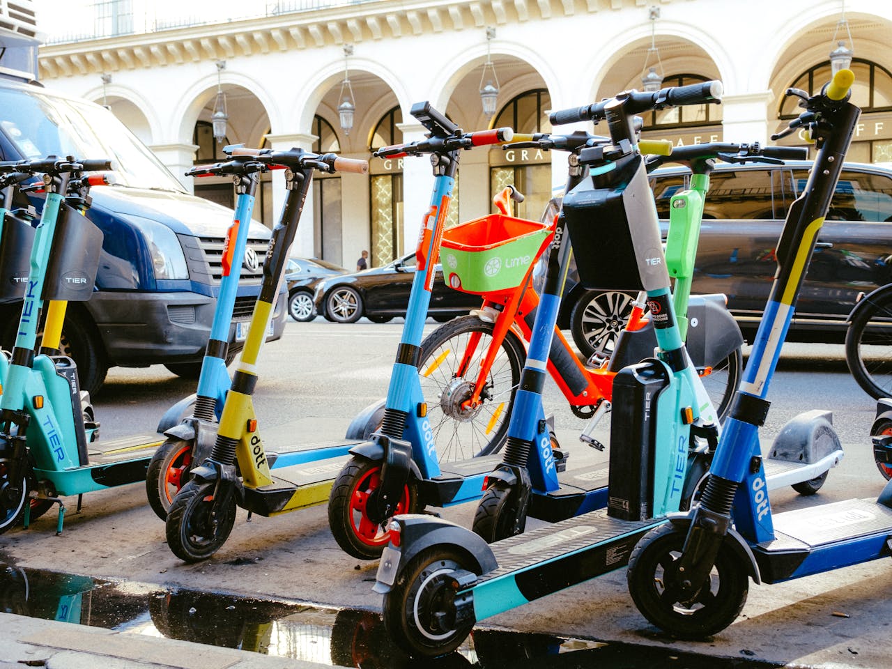 A vibrant collection of electric scooters and bicycles parked on a bustling city street.