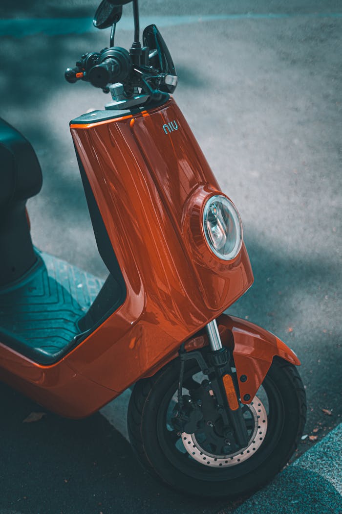 A close-up view of a red electric scooter parked on a city street, showcasing modern urban transportation.
